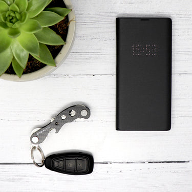 Picture of a Pocket Key Holder with car keys attached, laid on a table next to a plant