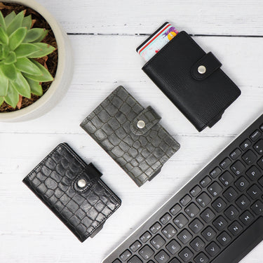 Picture of crocodile leather and pebble texture Avenger RFID Bifold Wallets laid out on a desk