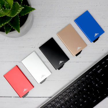 Row of 5 Raptor RFID Wallet with backplates lined up on a desk next to a computer keyboard